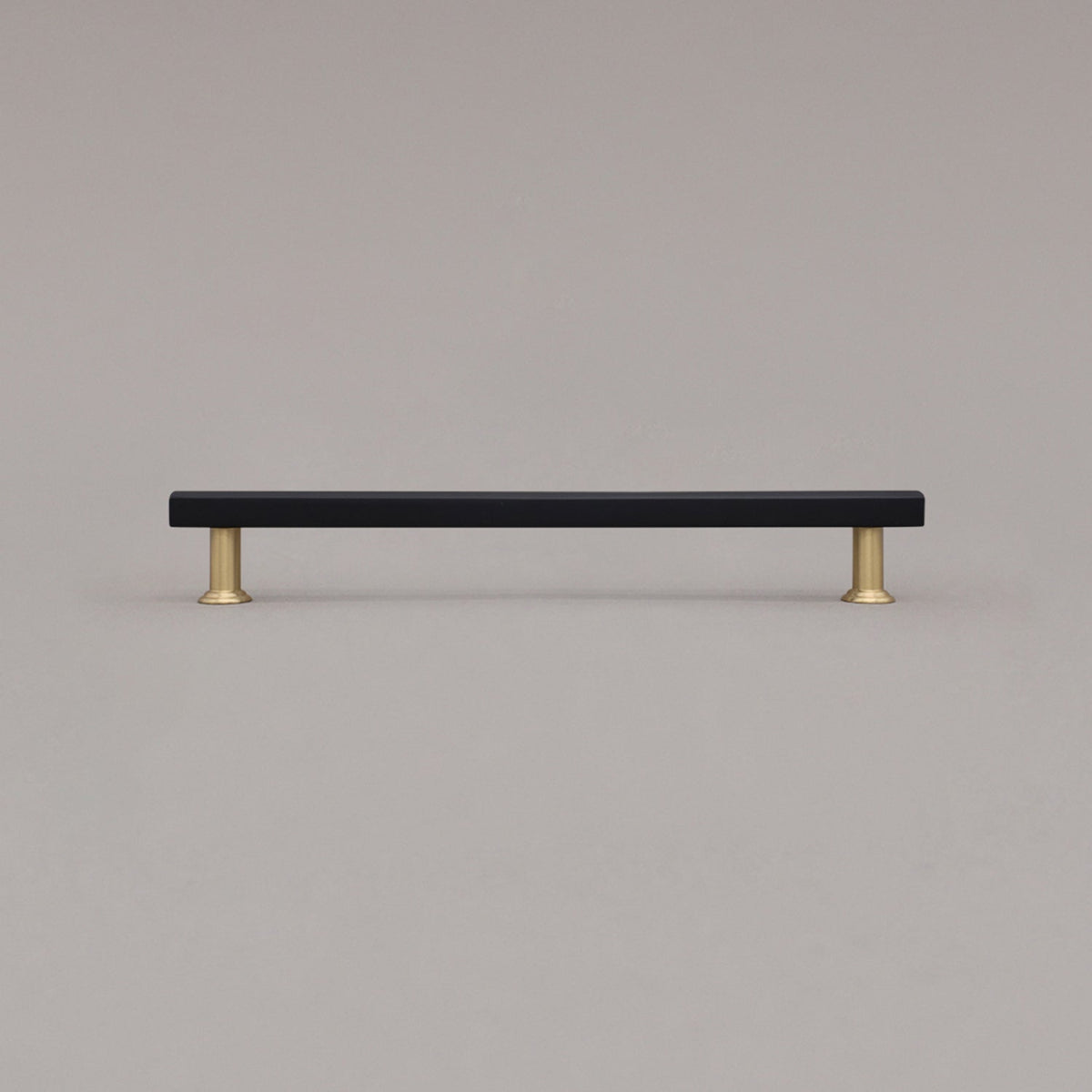 large matte black and satin brass mod cabinet pull standing on gray background
