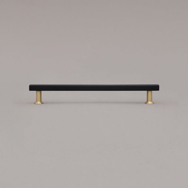 large matte black and satin brass mod cabinet pull standing on gray background