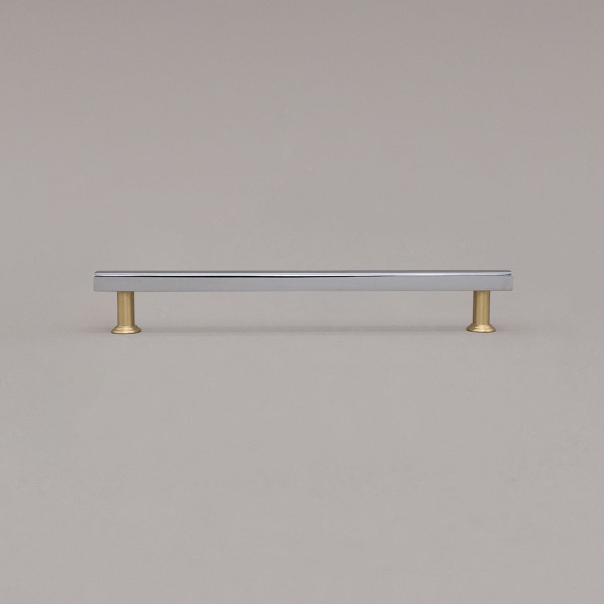 large polished chrome and satin brass mod cabinet pull standing on gray background