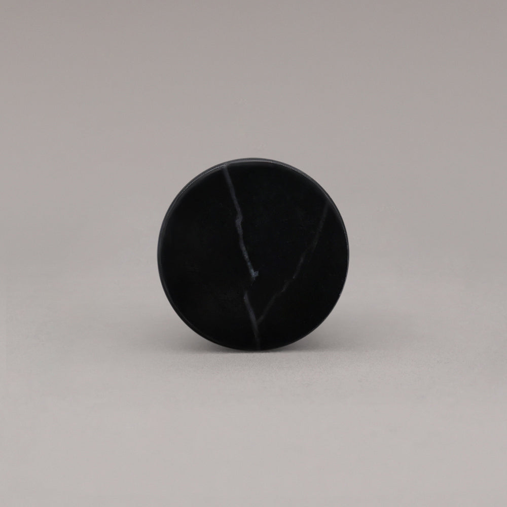 front view of black marble cone knob on gray background
