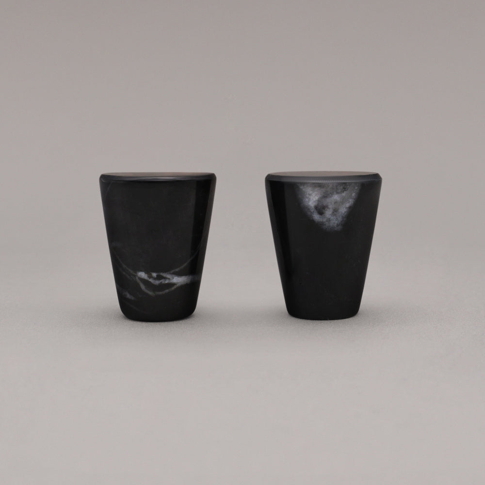 side view of two black marble cone knobs standing on gray background