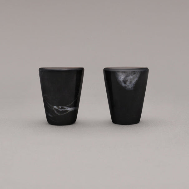 side view of two black marble cone knobs standing on gray background