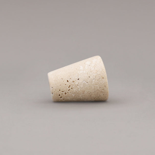 side view of travertine marble cone knob on gray background