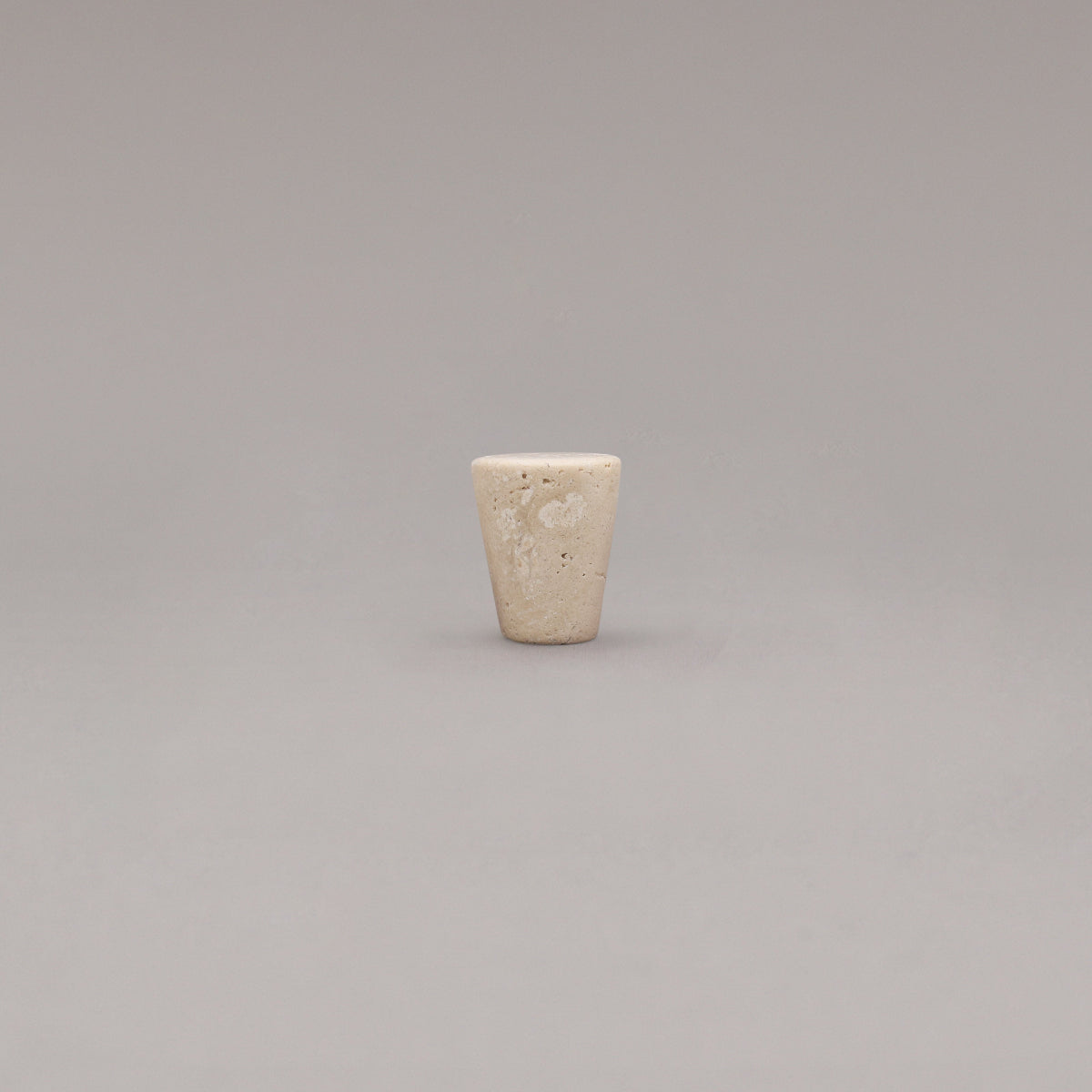 travertine marble cone knob standing on gray background
