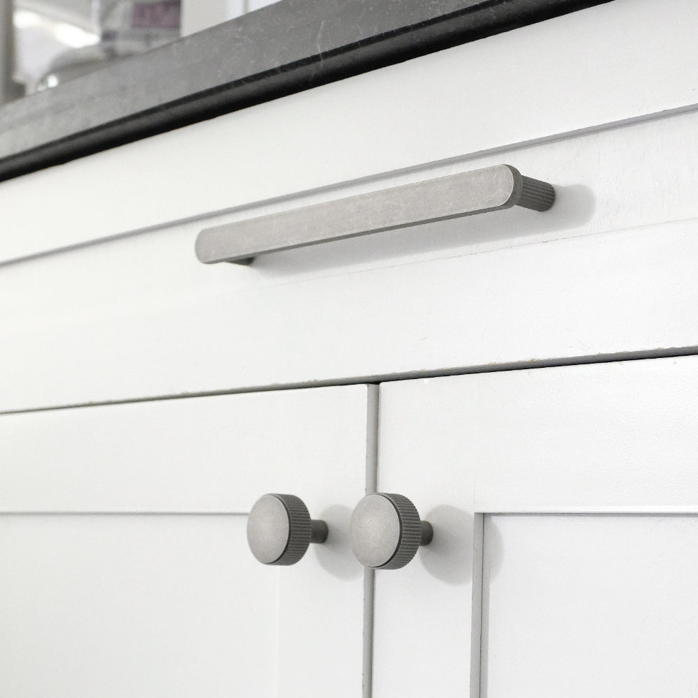 weathered nickel ribbed pull and knobs on white cabinet