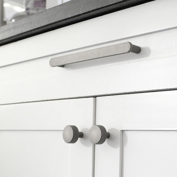 weathered nickel ribbed pull and knobs on white cabinet