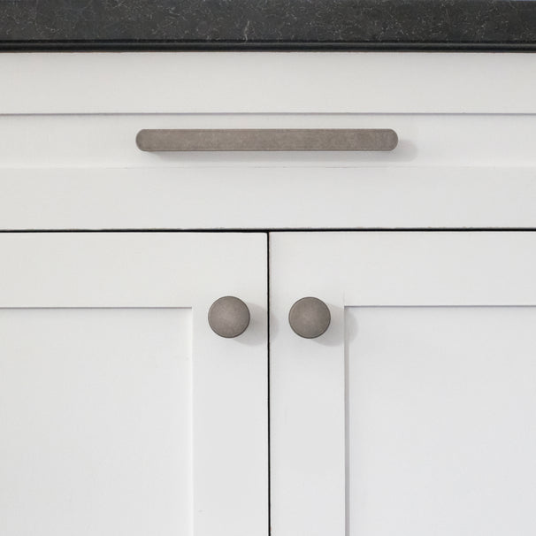 front view of weathered nickel ribbed pull and knobs on white cabinet