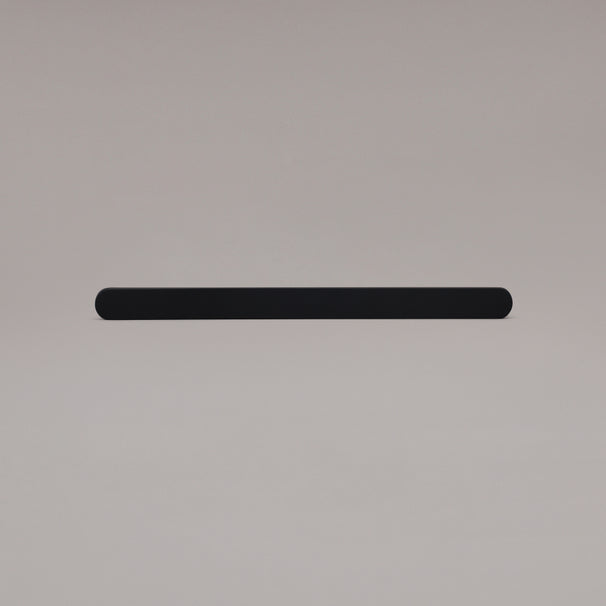 12" Ribbed appliance pull in Matte Black laying on gray background