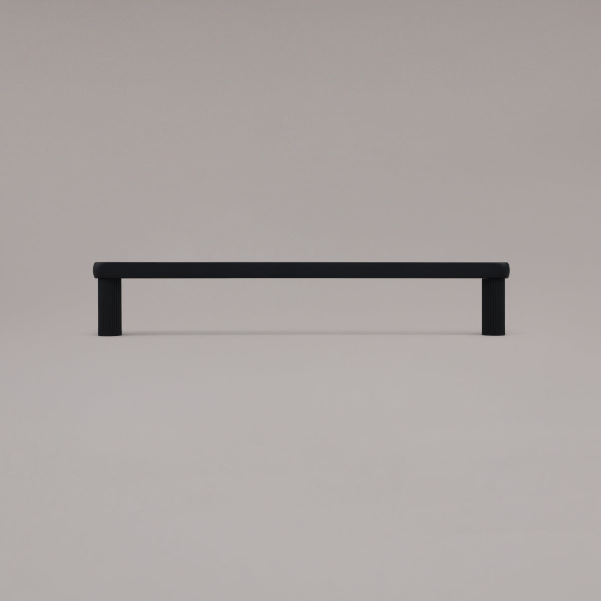 12" Ribbed appliance pull in Matte Black standing on gray background