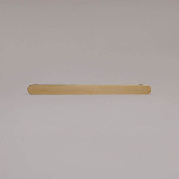 12" Ribbed appliance pull in Unlacquered Polished Brass laying on gray background