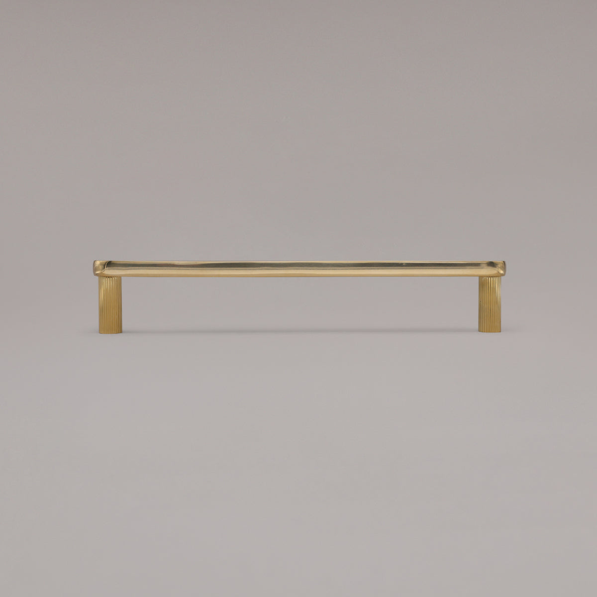 12" Ribbed appliance pull in Unlacquered Polished Brass standing on gray background
