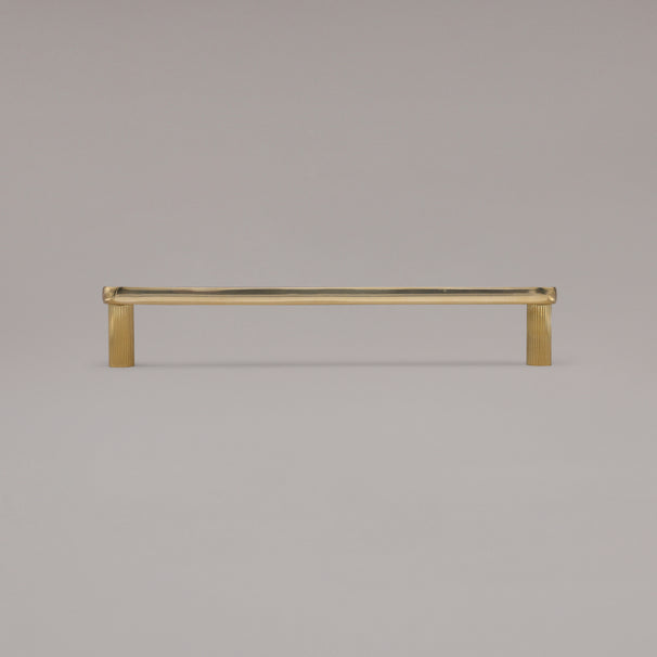 12" Ribbed appliance pull in Unlacquered Polished Brass standing on gray background