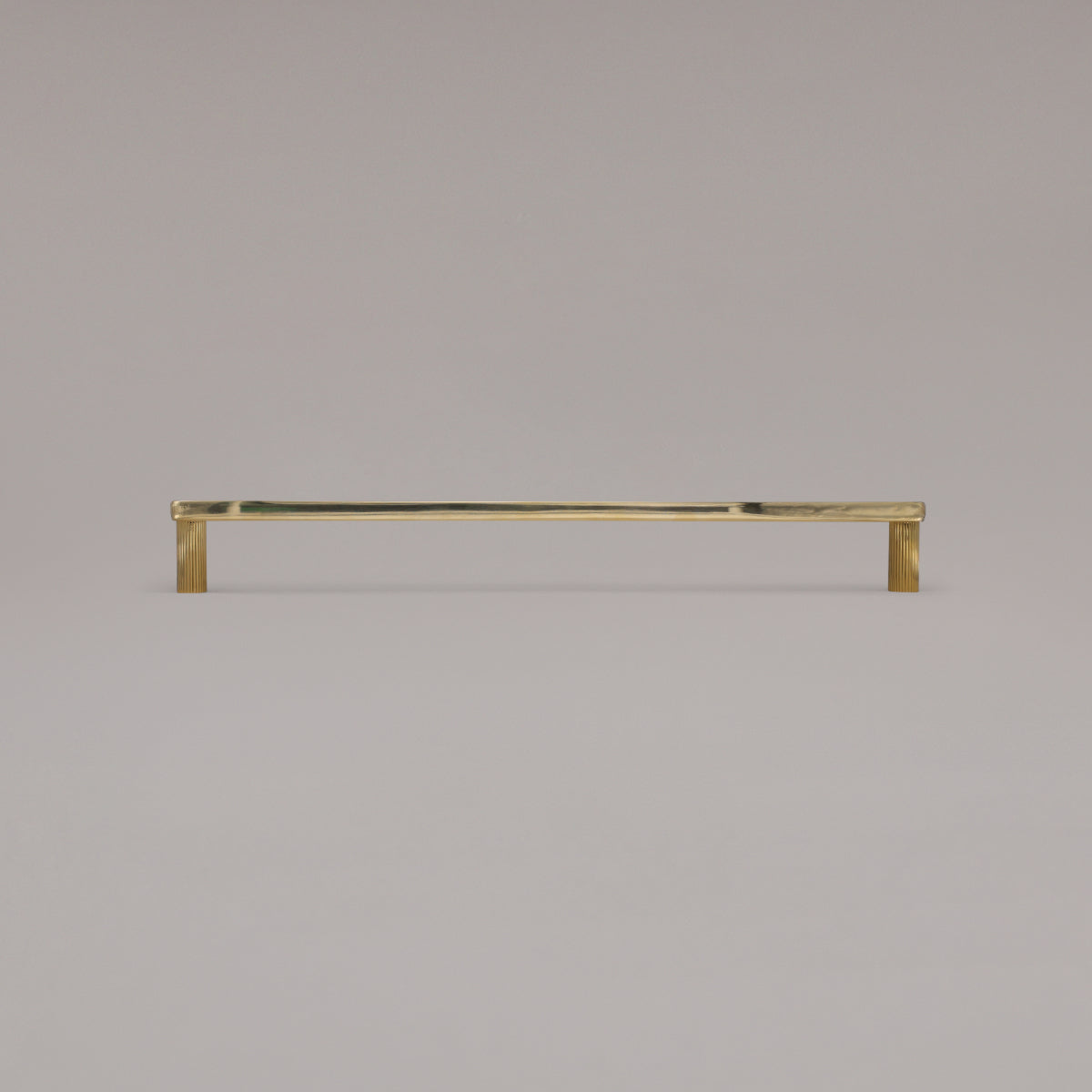 18" Ribbed appliance pull in Unlacquered Polished Brass standing on gray background
