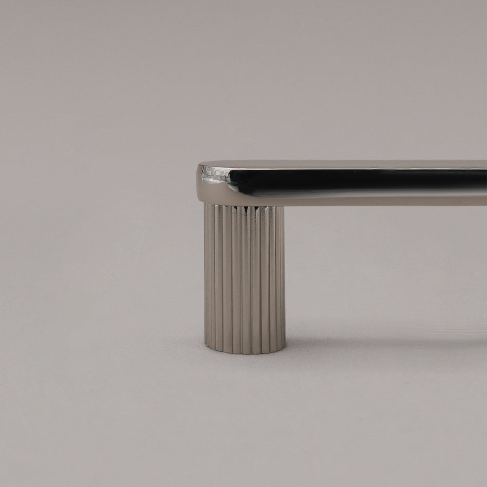 close up of polished nickel ribbed cabinet pull stem on gray background