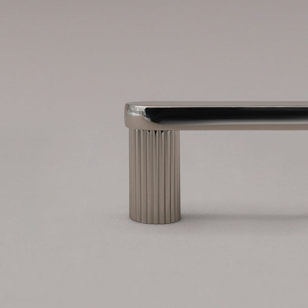 close up of polished nickel ribbed cabinet pull stem on gray background