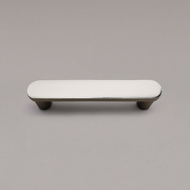 top view of small polished nickel ribbed cabinet pull on gray background
