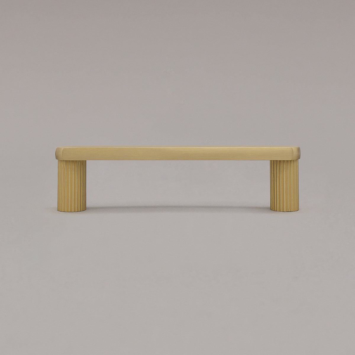 small satin brass gold ribbed pull standing on gray background