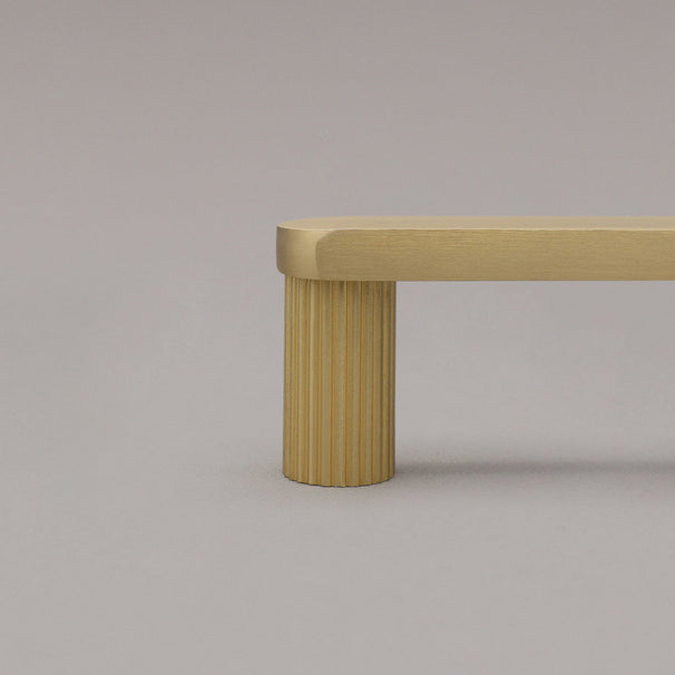 close up of ribbed satin brass gold stem on gray background