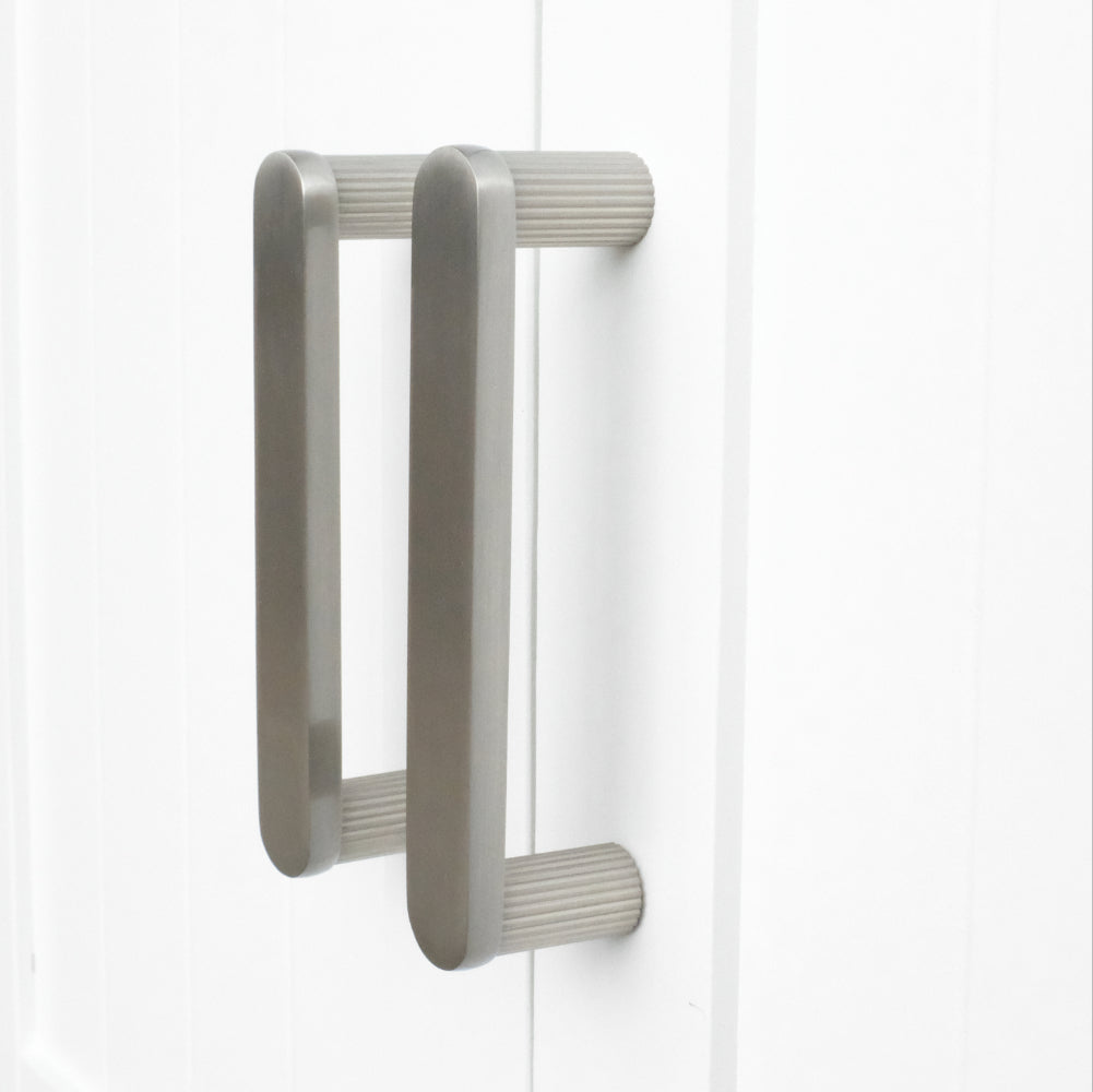 satin nickel ribbed pulls installed on white cabinets