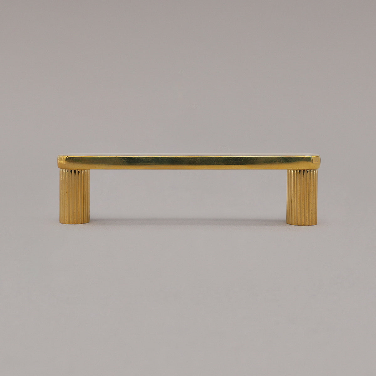 small unlacquered brass gold ribbed pull standing on gray background