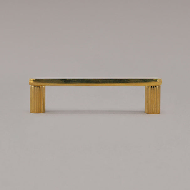small unlacquered brass gold ribbed pull standing on gray background