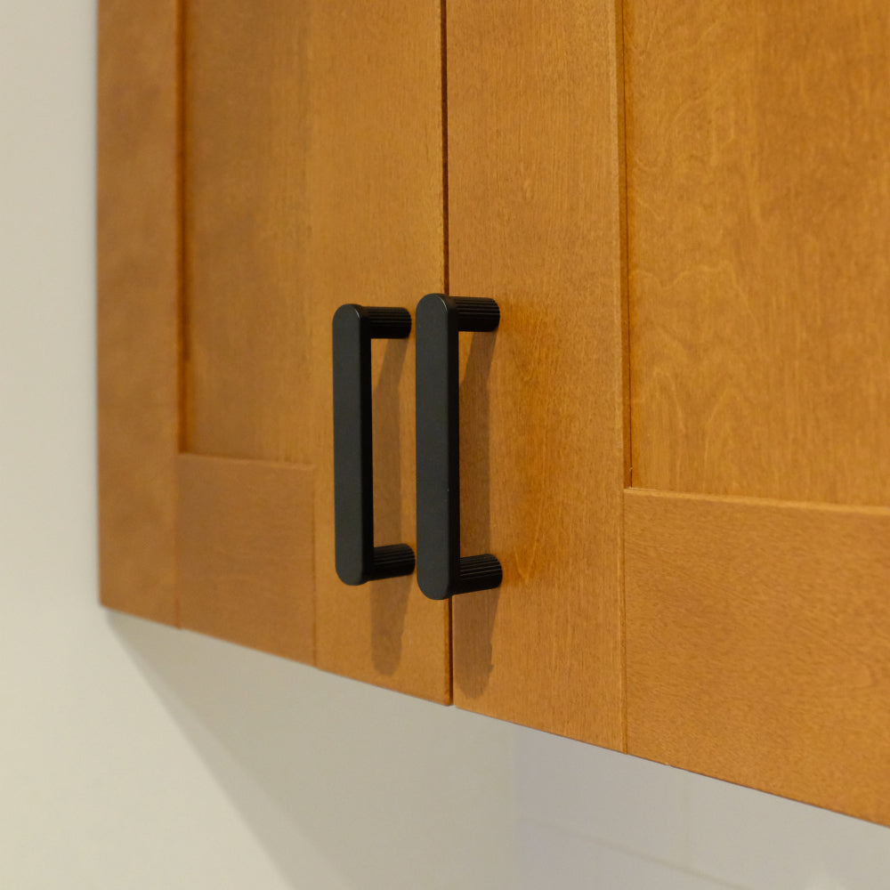 two matte black ribbed handles installed on wood cabinet