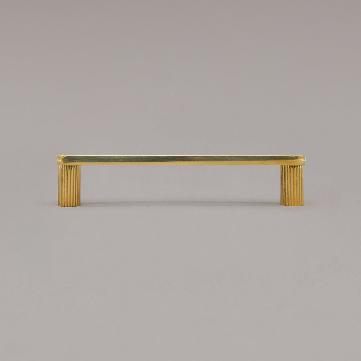 medium unlacquered brass gold ribbed pull standing on gray background