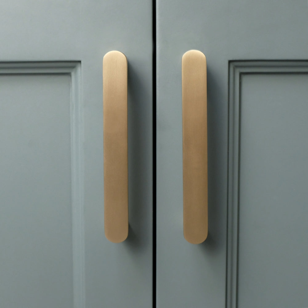 front view of ribbed satin brass gold cabinet pulls on blue cabinet