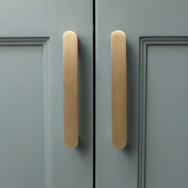 front view of ribbed satin brass gold cabinet pulls on blue cabinet