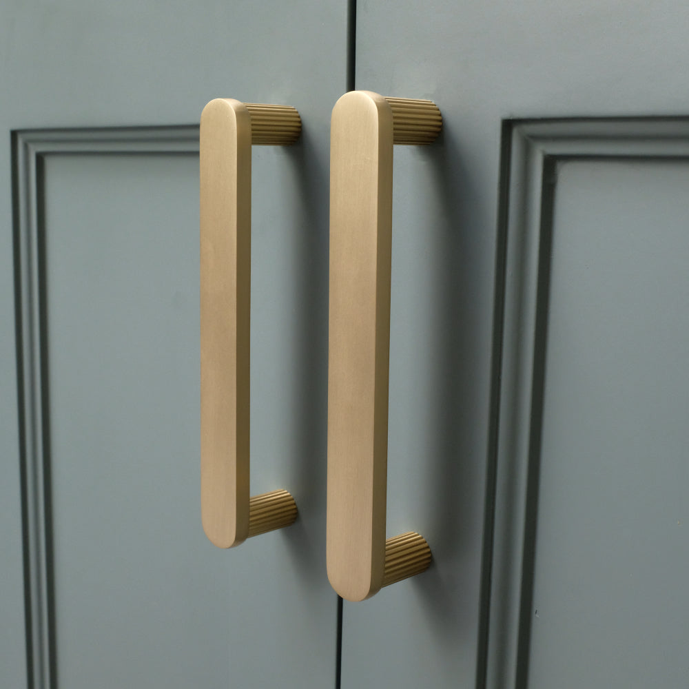 satin brass gold ribbed cabinet pulls installed on blue cabinets side view