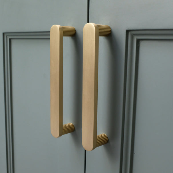 satin brass gold ribbed cabinet pulls installed on blue cabinets side view