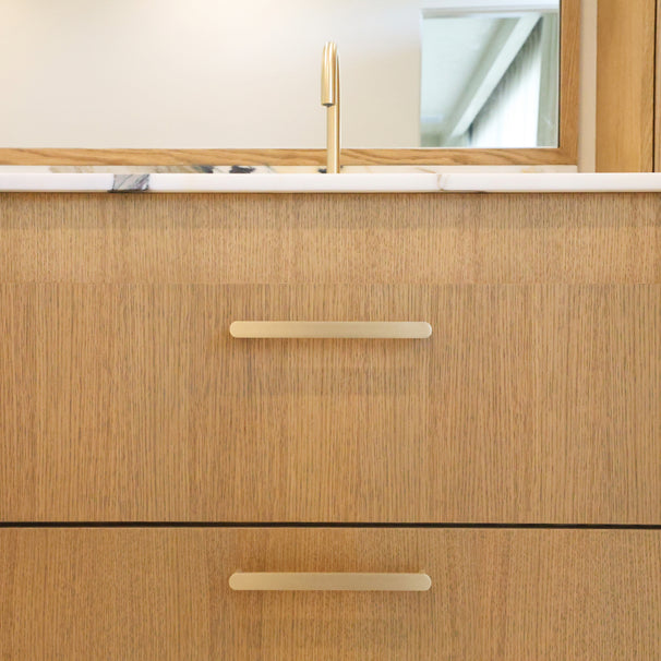 satin brass gold cabinet pulls installed on wooden cabinet