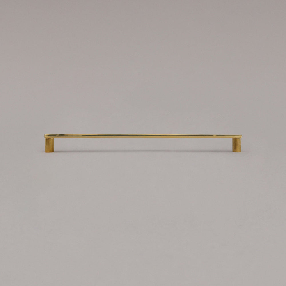 extra large ribbed unlacquered polished brass cabinet pull standing on gray background