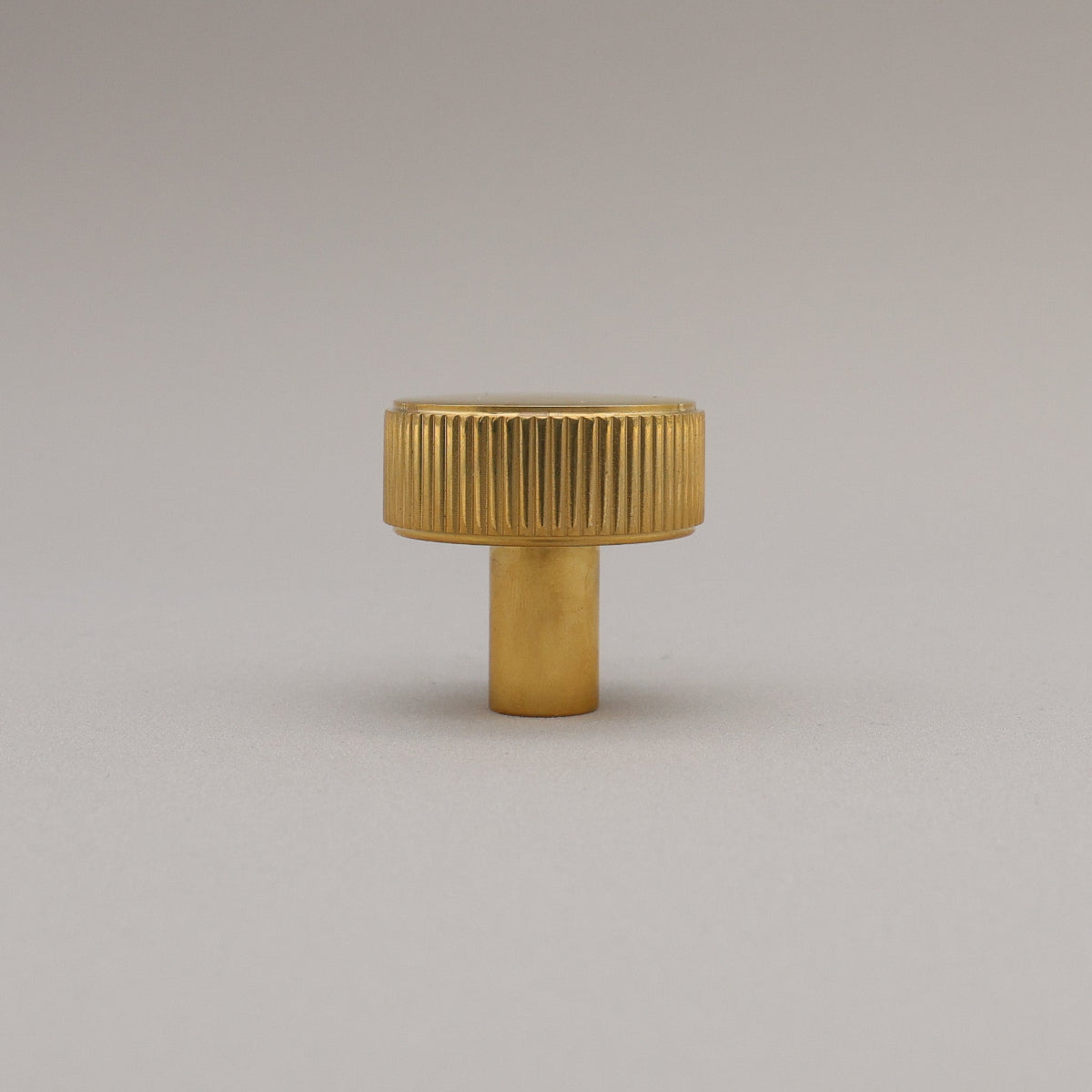 Unlacquered Polished Brass knob on a gray background