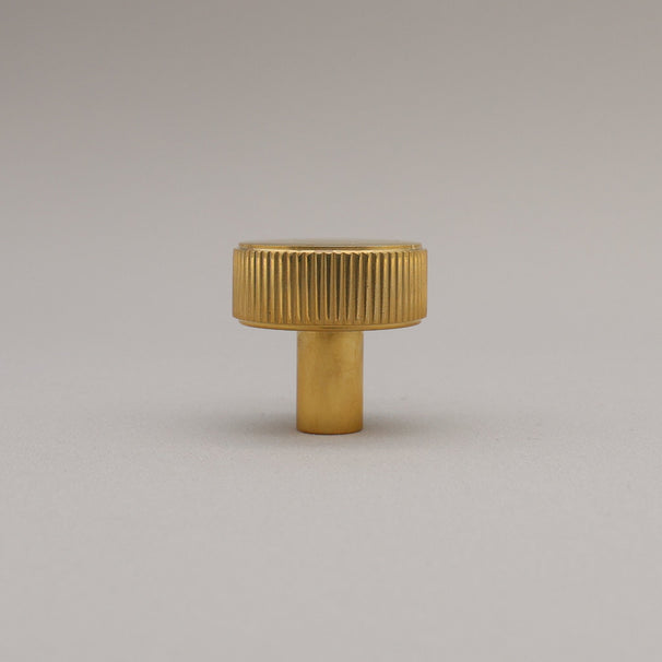 Unlacquered Polished Brass knob on a gray background
