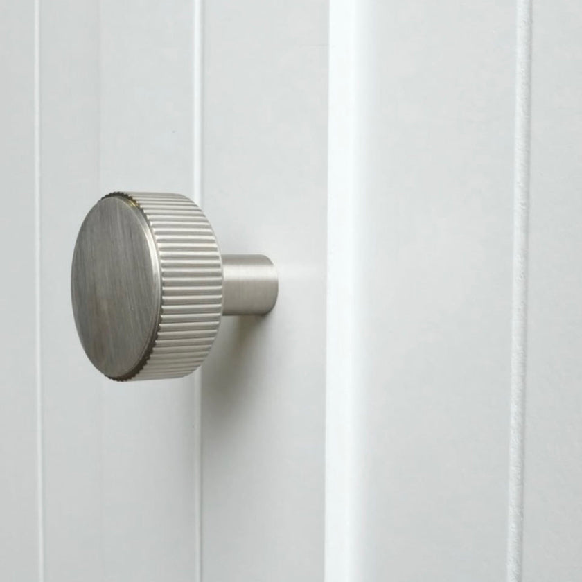satin nickel silver textured ribbed knob with fluting detail installed on a white cabinet