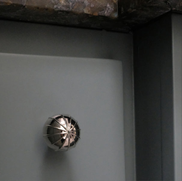 Sunburst polished nickel round knob installed on blue bathroom drawer