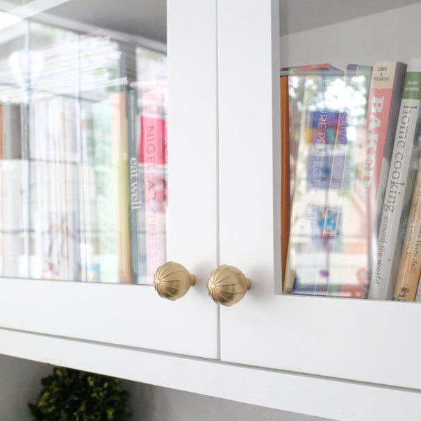 Sunburst round knobs in satin brass gold installed on white kitchen cabinets