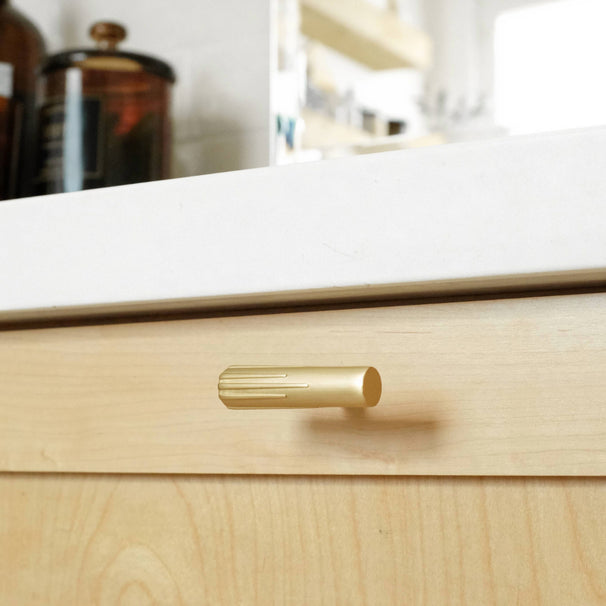 Sunburst t-knob in satin brass on light wood bathroom drawer