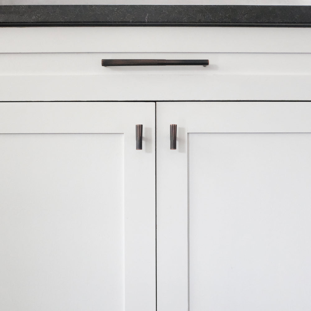 Venetian bronze sunburst cabinet pull and t-knobs installed on white cabinets
