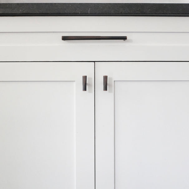 Venetian bronze sunburst cabinet pull and t-knobs installed on white cabinets