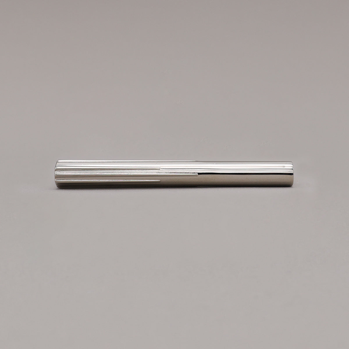 small polished nickel sunburst pull laying on gray background