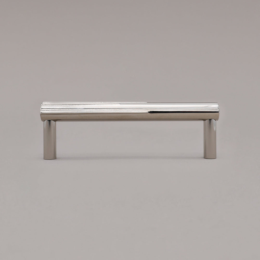 small polished nickel sunburst pull standing on gray background