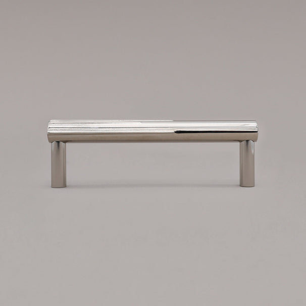 small polished nickel sunburst pull standing on gray background