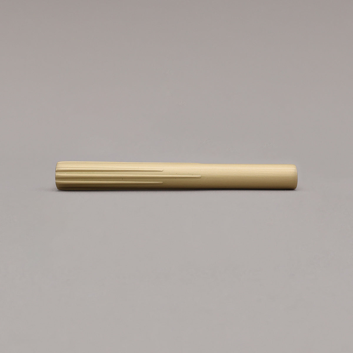 small satin brass sunburst pull laying on gray background