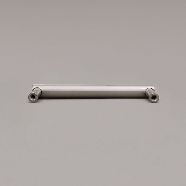 rear view of small silver satin nickel sunburst cabinet pull on gray background