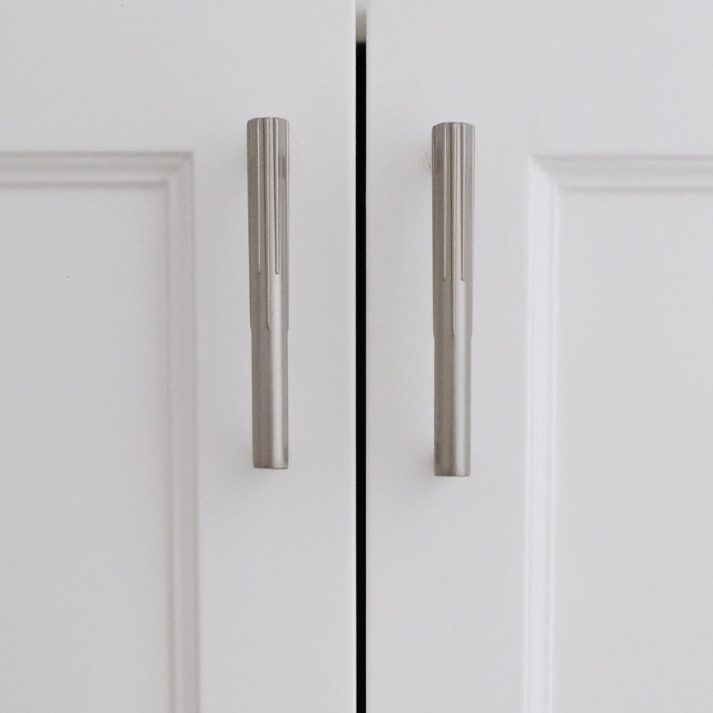 Small silver sunburst satin nickel cabinet pulls installed on white cabinet