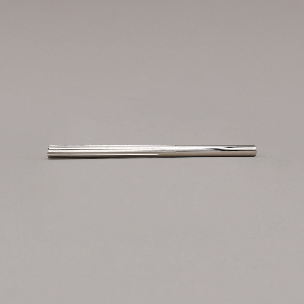 large polished nickel sunburst pull laying on gray background