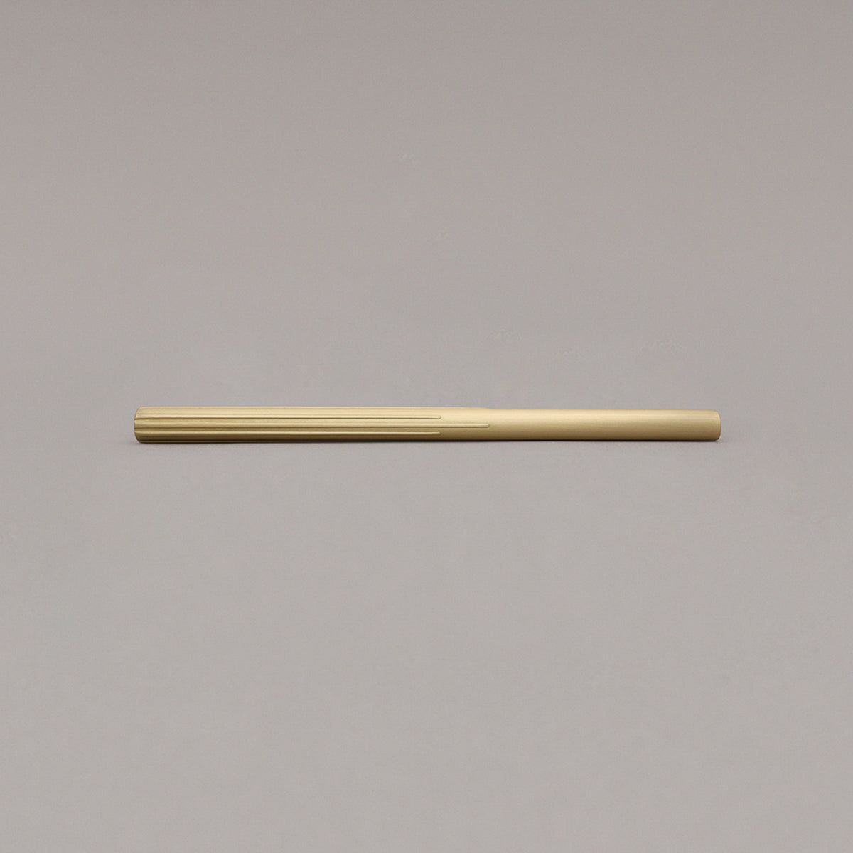 large satin brass sunburst pull laying on gray background