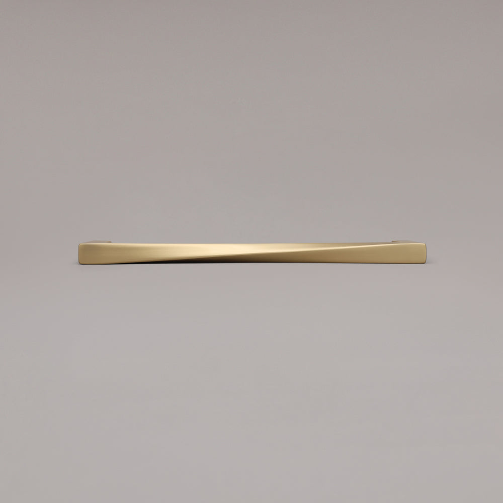 12" Twist appliance pull in Satin Brass laying on gray background
